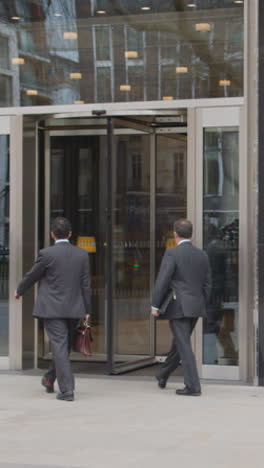 Vídeo-Vertical-De-Un-Hombre-Caminando-Hacia-Un-Edificio-De-Oficinas-Con-Puerta-Giratoria-En-Mayfair,-Londres,-Reino-Unido